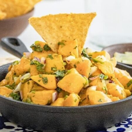 mango salsa in a bowl with chip poked in