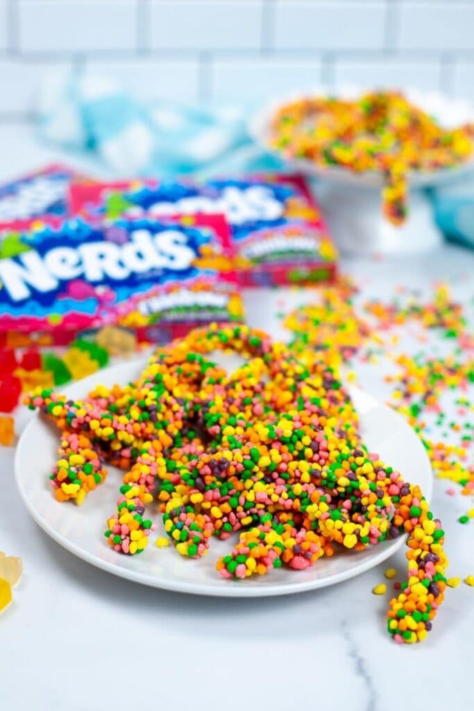 rainbow candy ropes on a plate with boxes of candy behind it 