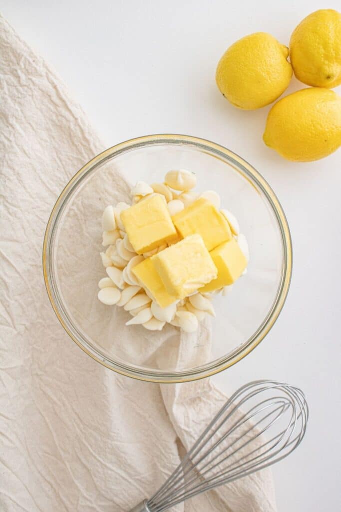 white chocolate chips and butter in bowl with whisk by it 