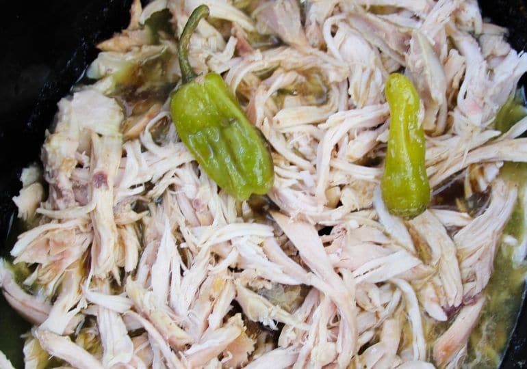 Overhead shot of shredded chicken and peppers in crockpot