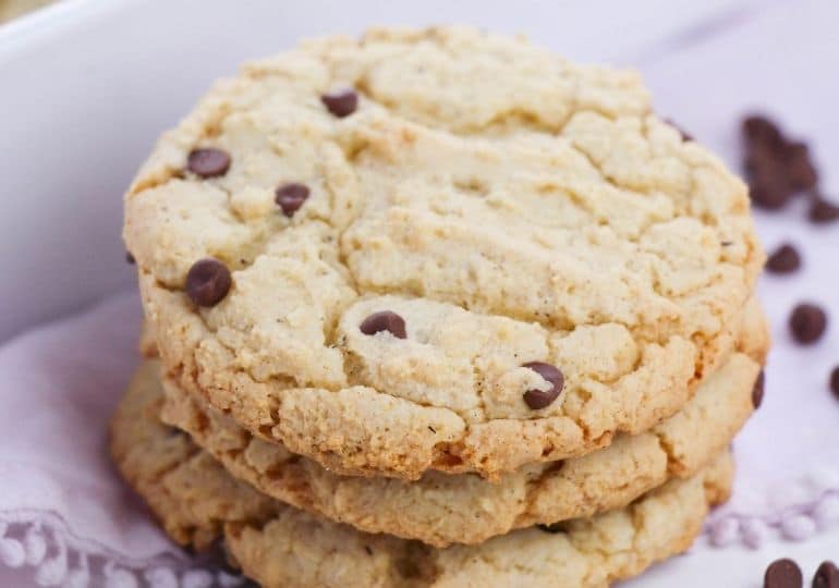 chocolate chip cookies stacked on table with mini chocolate chips around it