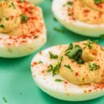 deviled eggs on a green plate, topped with garnish
