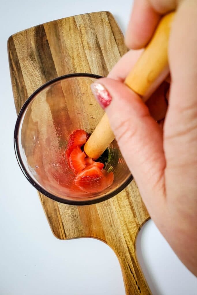 muddling mint and strawberries in glass