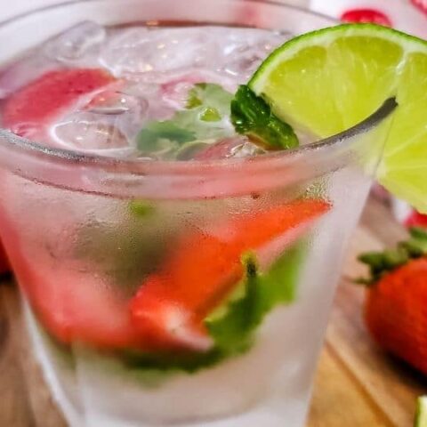 strawberry mojito in a glass garnished with a lime wedge on table