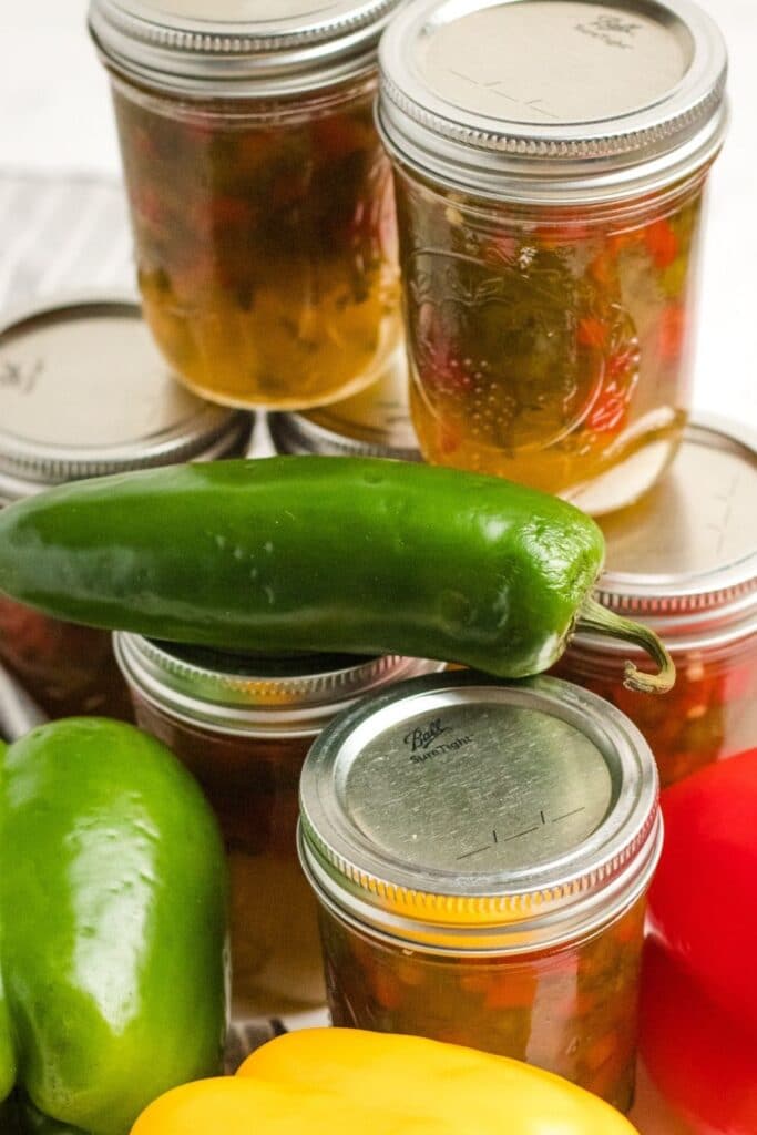 sweet pepper jelly stacked on top of each other with peppers around it