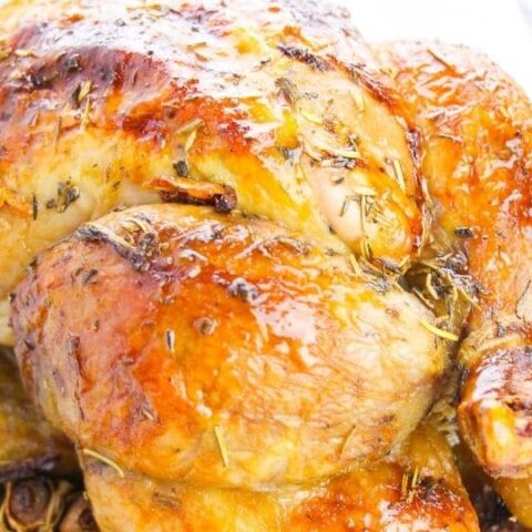 Platter with whole chicken on it, topped with herbs