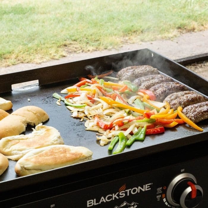 Brats with peppers and onion mixture and hoagies on griddle grill