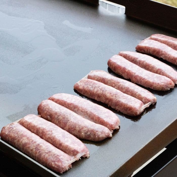 brats cut and split face down on blackstone grill