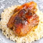 chicken thigh on plate with rice under it