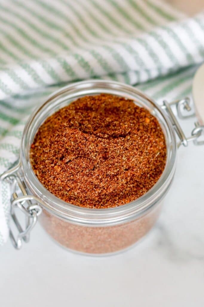 seasoning mix in a glass jar with towel behind it 