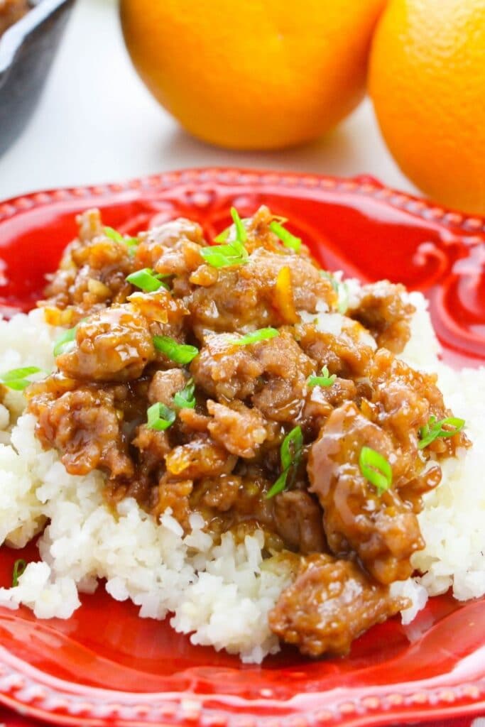 plate with rice and orange chicken on top garnished