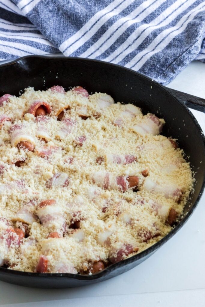 brown sugar on top of bacon wrapped smokies in cast iron skillet