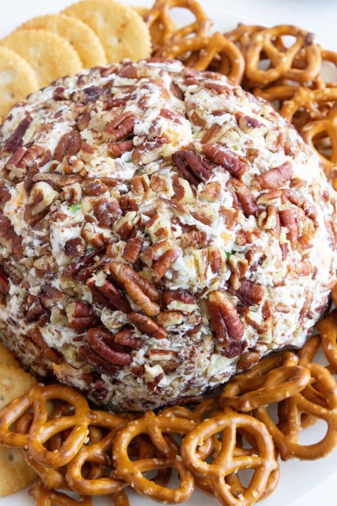 pecan cheese ball on plate with crackers and pretzels around it 