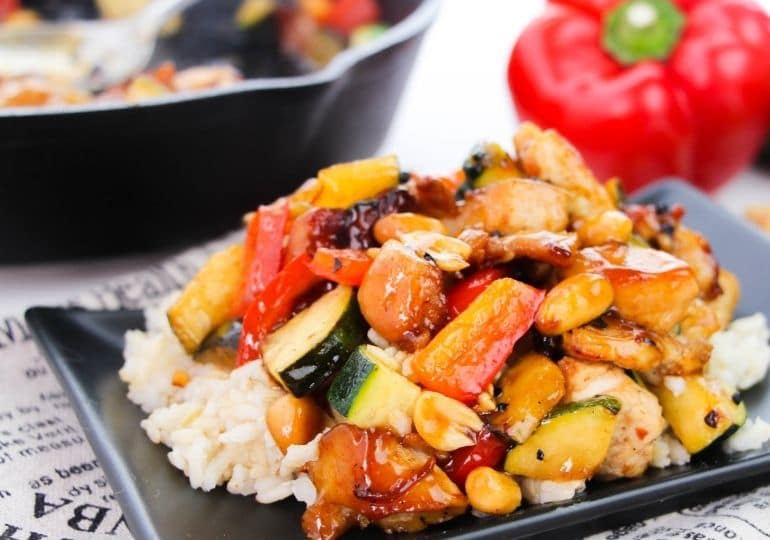 kung pao chicken on a platter with rice under it