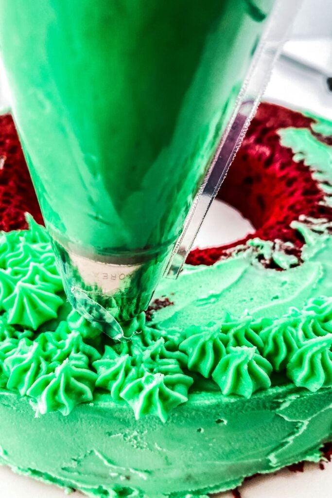 piping green frosting on cake 