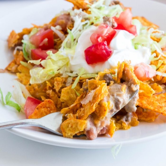 plate of dorito casserole with lettuce and tomato topping 