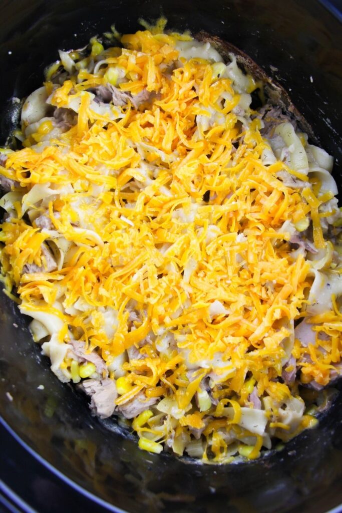 cheesy tuna noodles in crockpot with cheese on top 