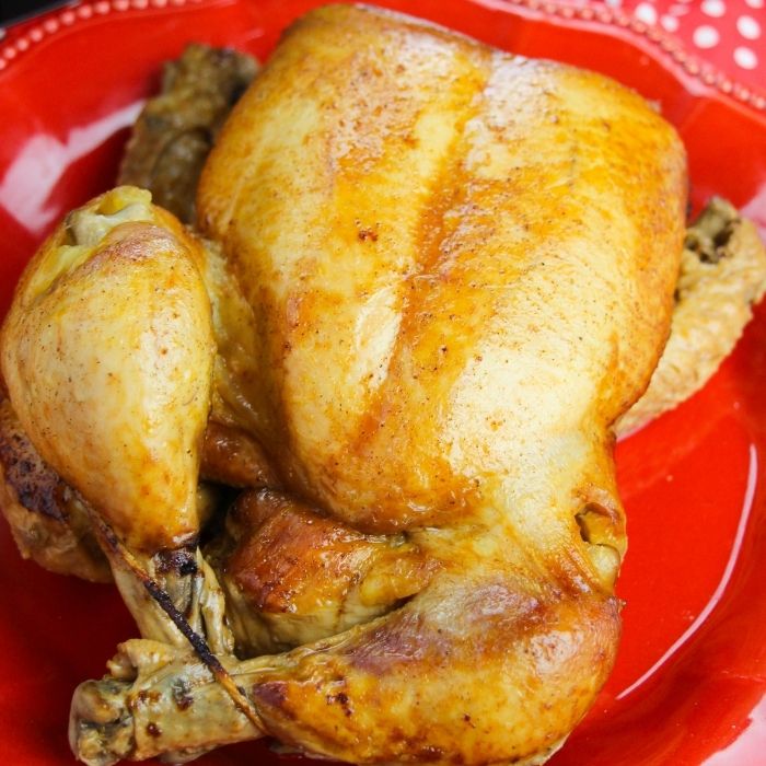 whole chicken on a red plate on table