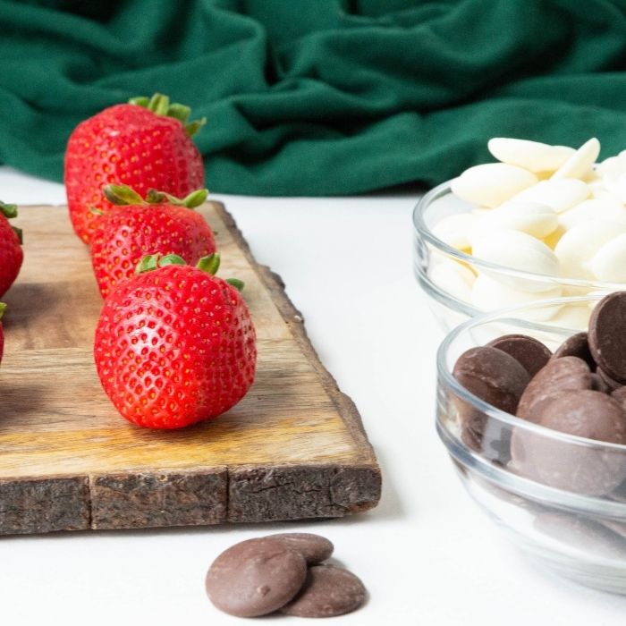 strawberries and chocolate melts in bowls on white table 