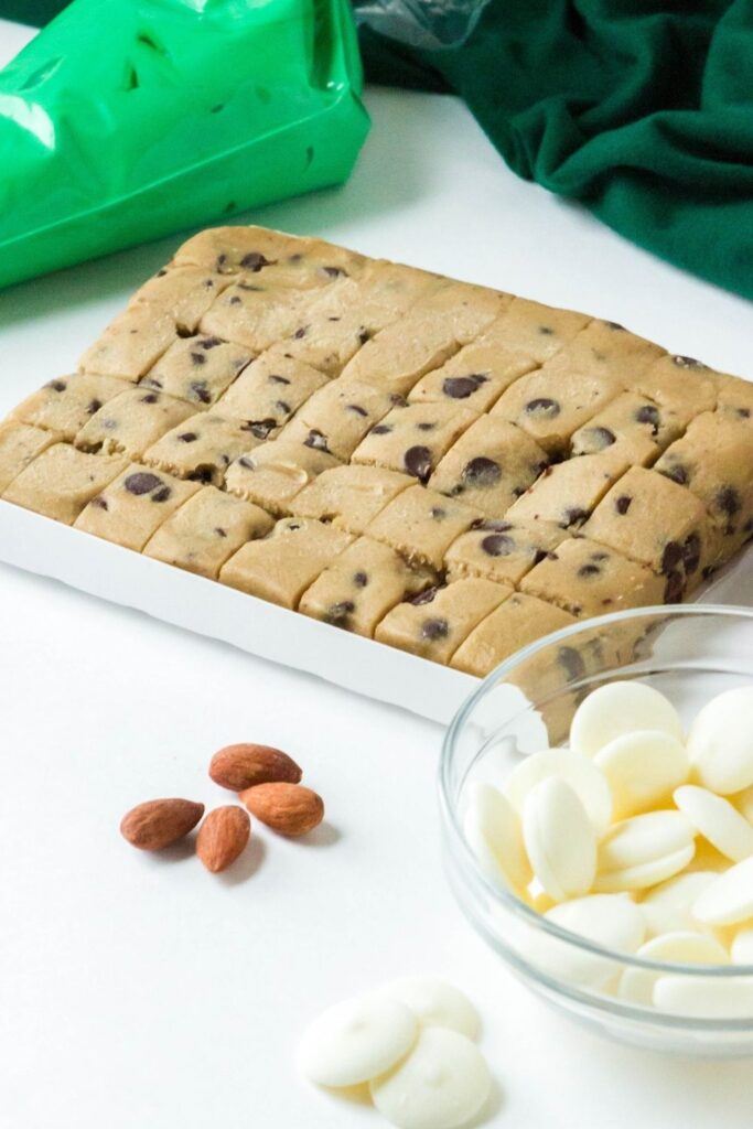 raw cookie dough, white wafers, almonds and frosting on white counter 