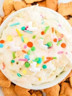 cheesecake dip with sprinkles on top with cookies around bowl