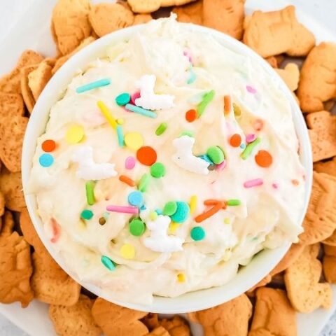 cheesecake dip with sprinkles on top with cookies around bowl
