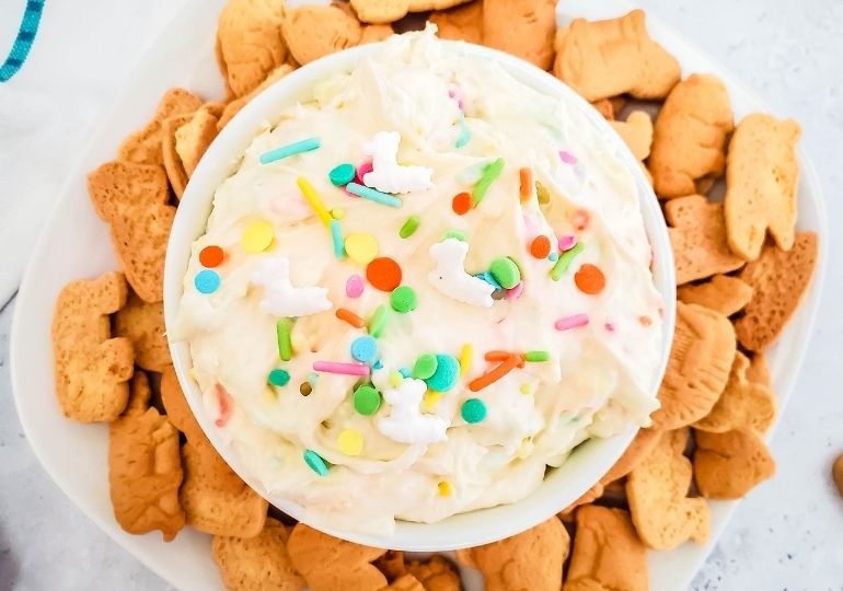 cheesecake dip with sprinkles on top with cookies around bowl