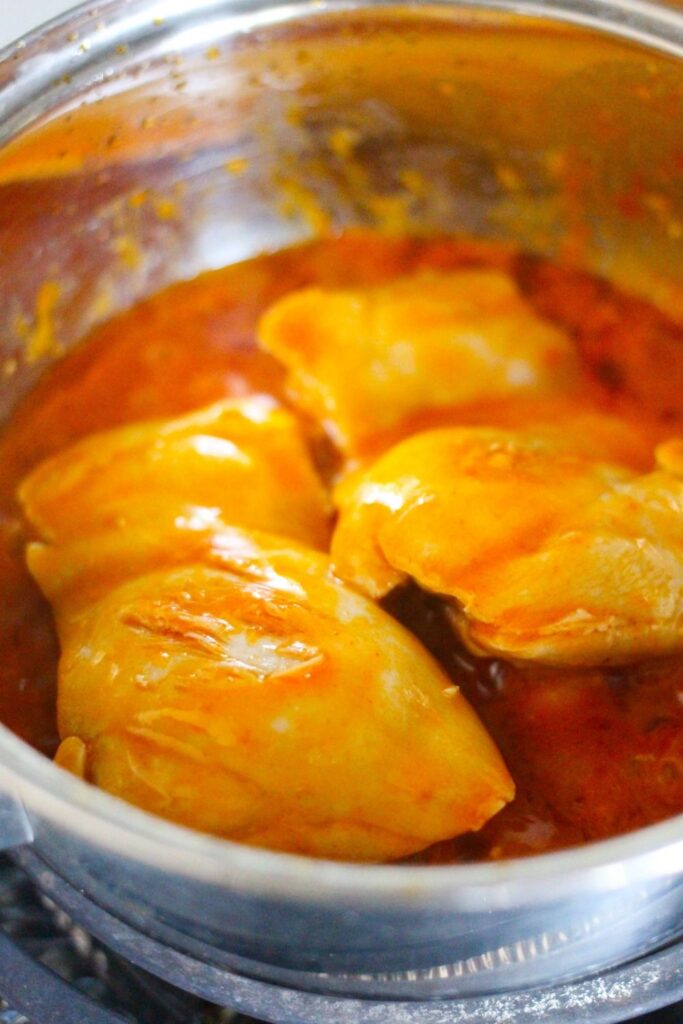 chicken in a pan with hot sauce cooking 