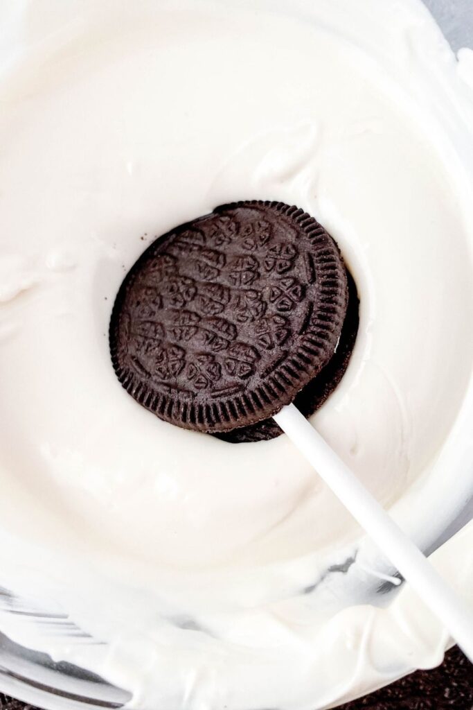 Oreo dipping into white chocolate in bowl 