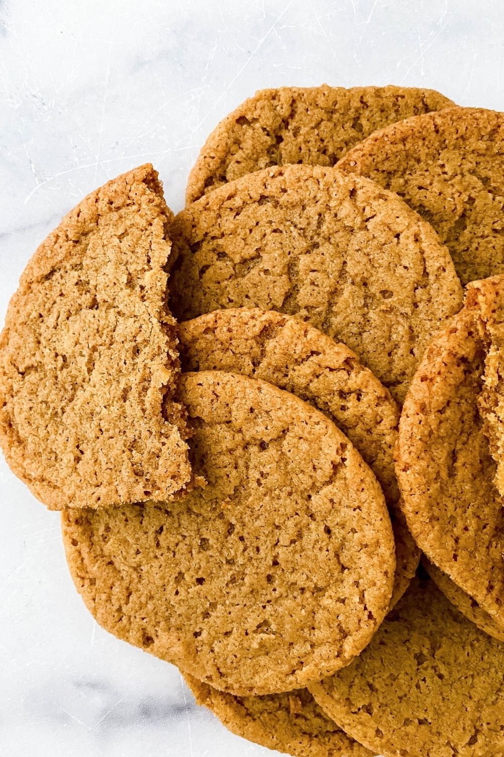 homemade ginger cookies on marble counter with cookie broken apart on counter