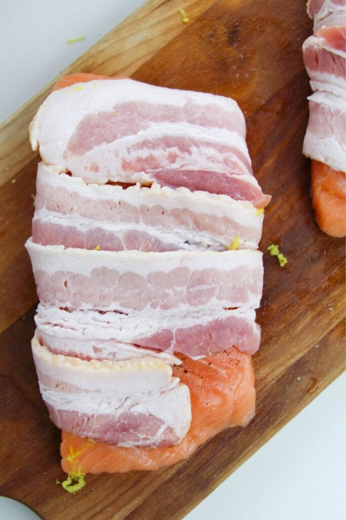 salmon wrapped in bacon on cutting board