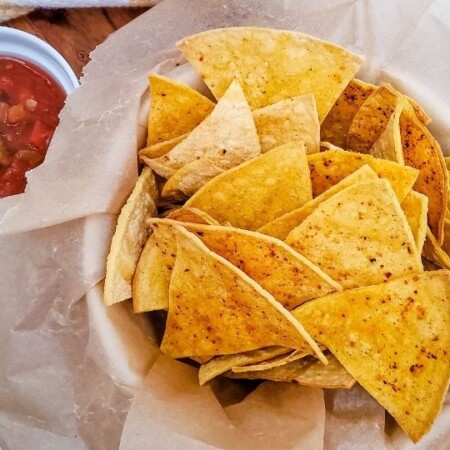 corn tortilla chips in basket with salsa by it