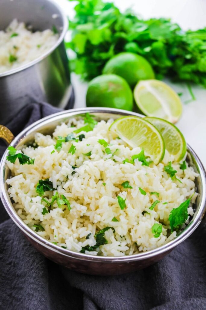 lime cilantro rice in bowl with lime and cilantro behind it 