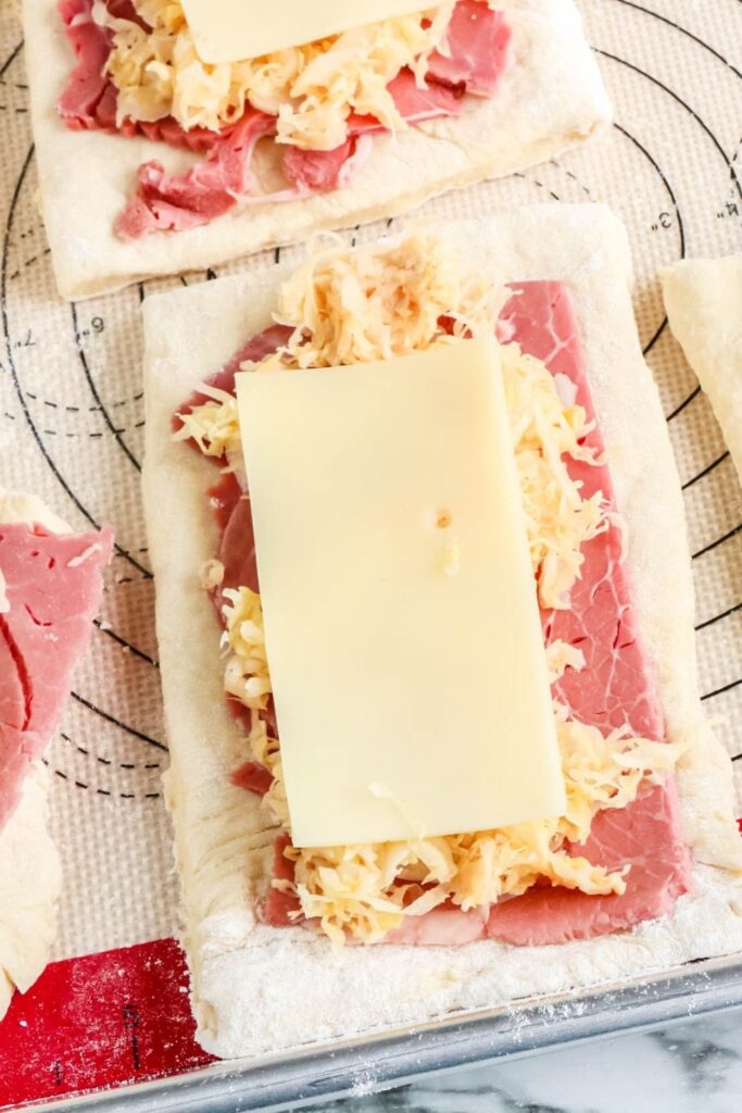 reuben ingredients on raw pizza dough rectangles 