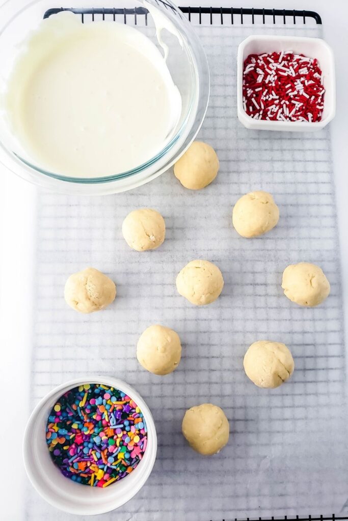 sugar cookie truffles on lined cooling rack with chocolate in a bowl