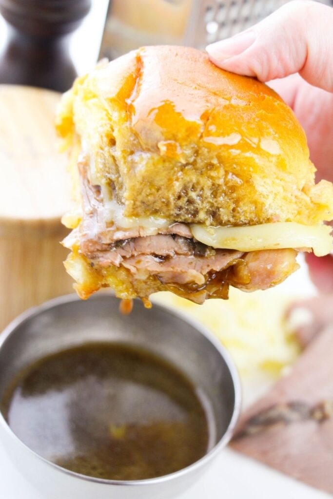 roast beef sliders with au jus sauce in a container by it 