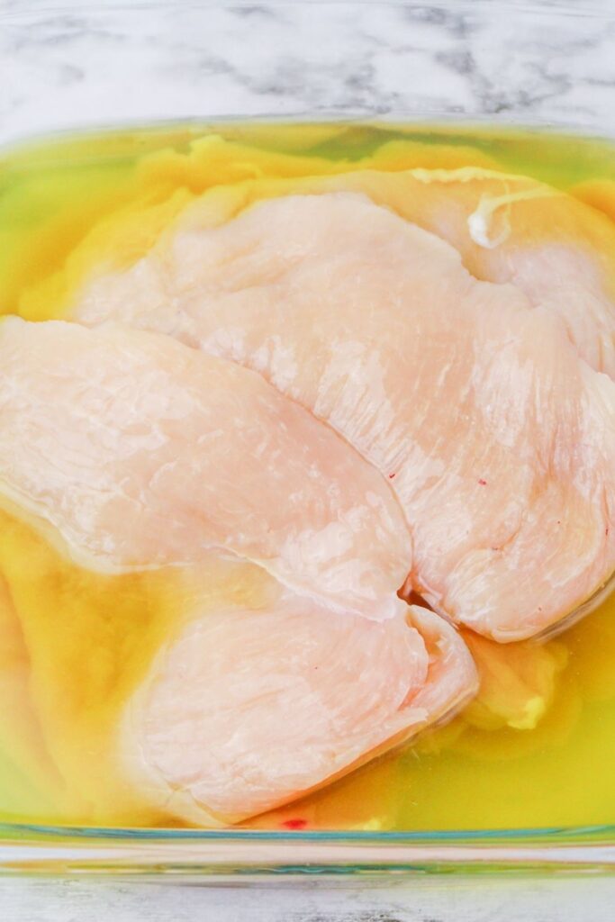 chicken soaking in pickle juice in glass container 