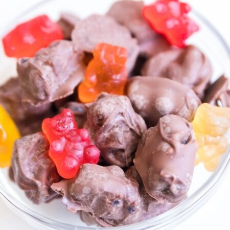chocolate covered gummy bears in a glass bowl on white table