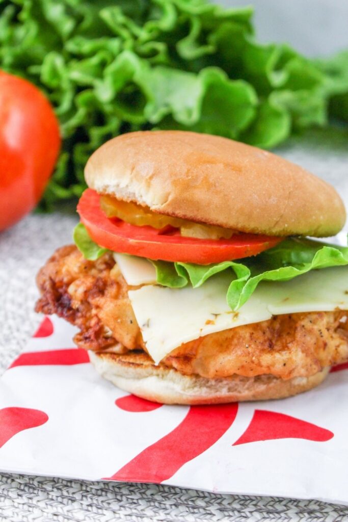 crispy chicken sandwich on table with lettuce behind it 