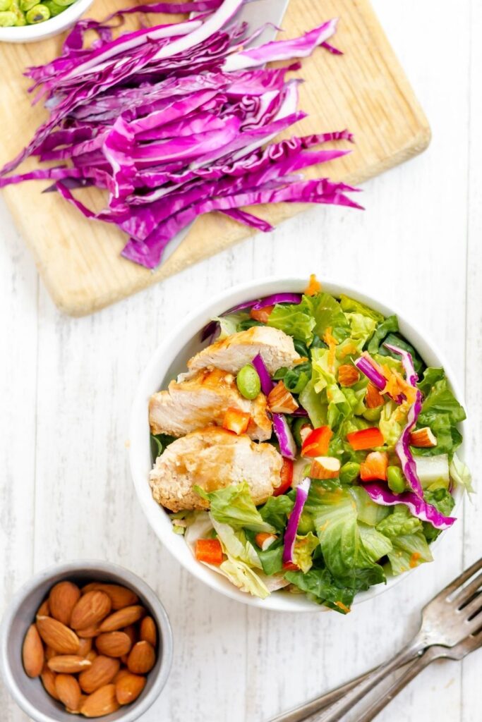 overhead shot of salad, nuts, and cutting board with cabbage 