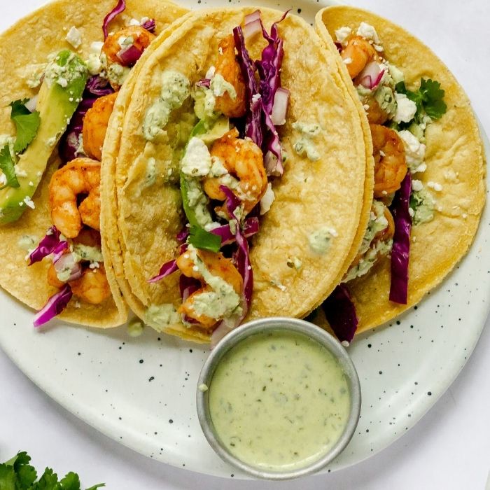 plate with 3 shrimp tacos and crema sauce 