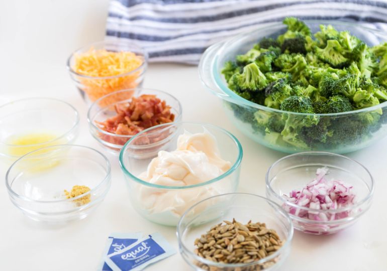 broccoli salad ingredients in bowls on white counter 