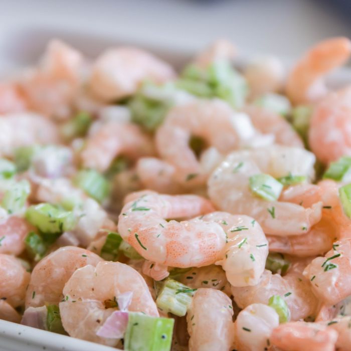 cold shrimp salad in a serving bowl on white table 