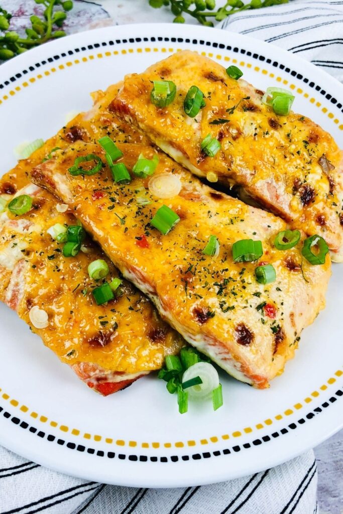 salmon filets on a plate with green onions on top 