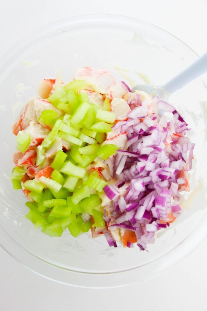 celery and onions on top of crab meat in a bowl 