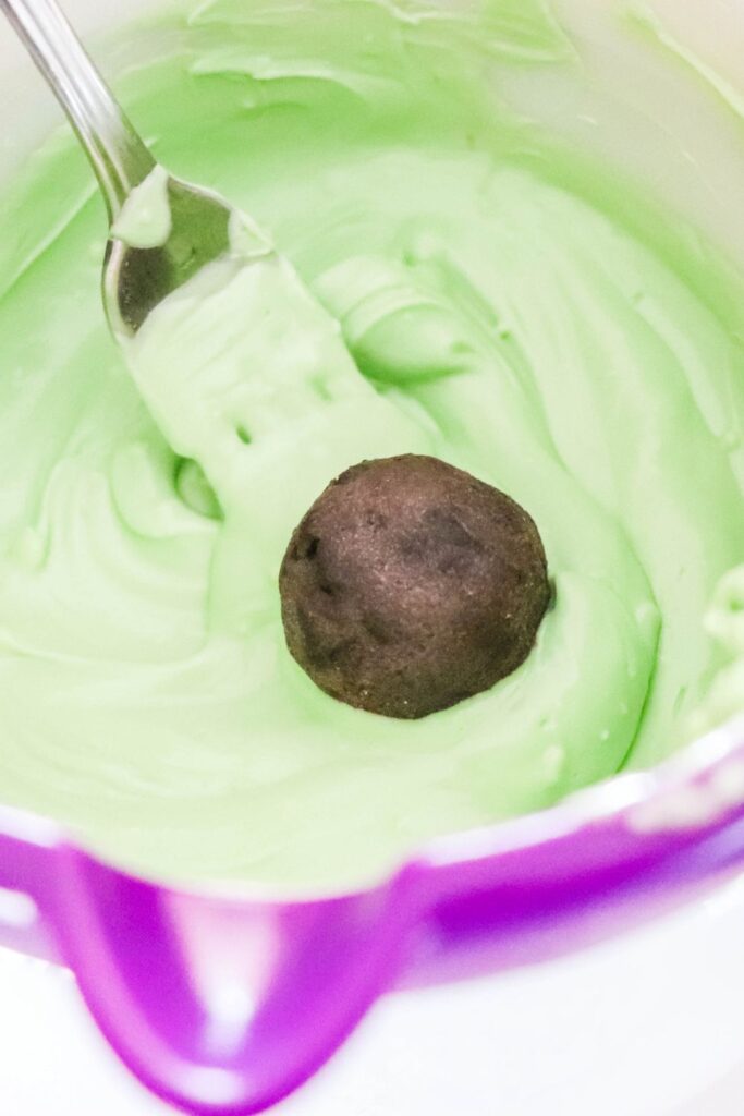 Oreo ball in a bowl of melted green chocolate 