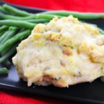 swiss chicken on plate with green beans on it placed on table