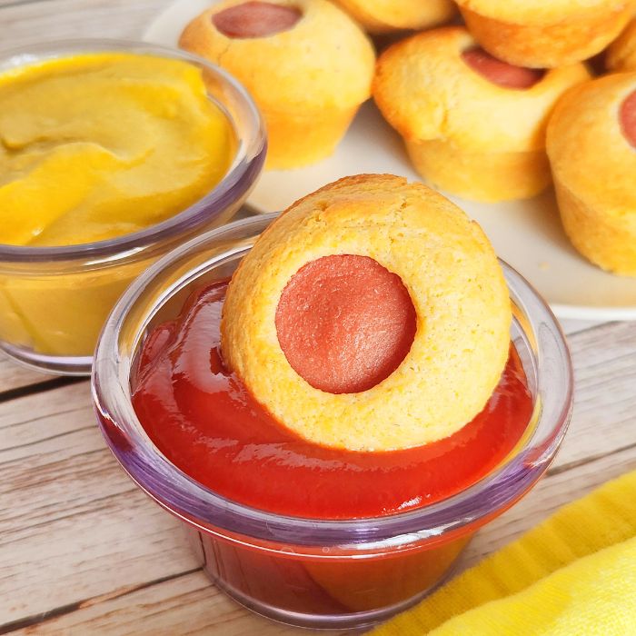 mini corn dog muffin dipped in a bowl of ketchup 