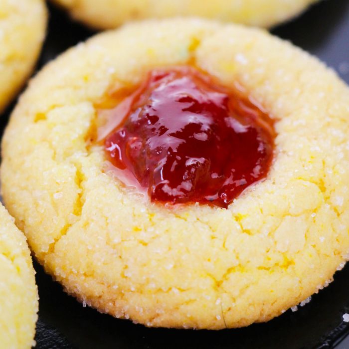 close up of a lemon thumbprint cookie on black plate