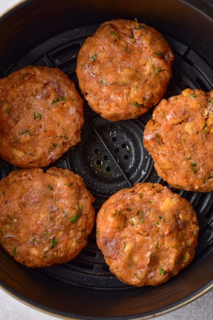 raw salmon patties in an air fryer basket